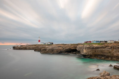 Lighthouse by sea against sky