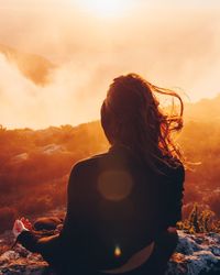 Rear view of woman against sky during sunset