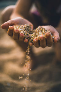 Cropped hands spilling sand at beach