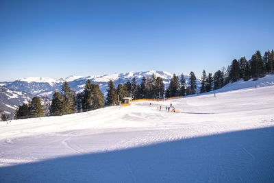 People skiing on snow covered mountain against clear sky