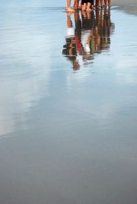 Low section of woman walking on wet beach in city