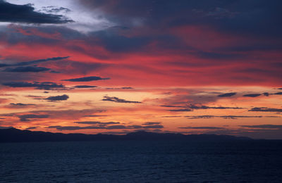 Scenic view of sea against dramatic sky during sunset