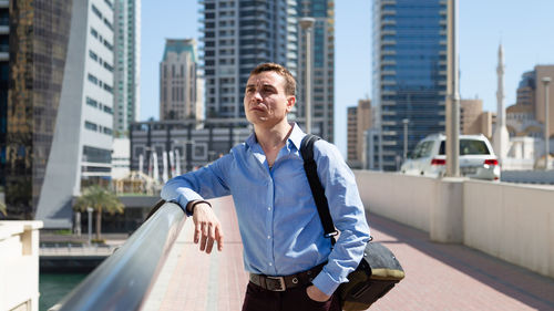 Young man standing against buildings in city