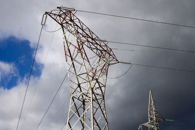 Low angle view of electricity pylon with sky background