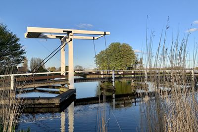 Built structure by river against clear blue sky