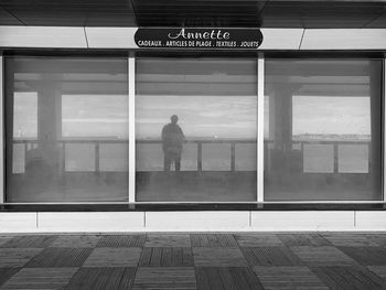 Rear view of man standing on glass window