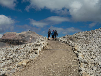 Rear view of man walking on mountain against sky