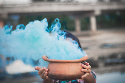 Woman holding smoke emitting from pottery