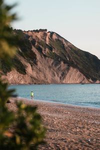 Distant view of man at beach against mountain