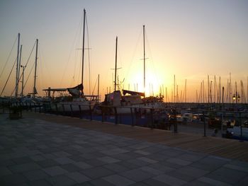 Sailboats moored at harbor during sunset