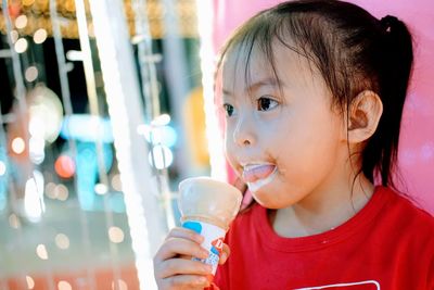 Close-up of cute girl looking away while holding ice cream cone