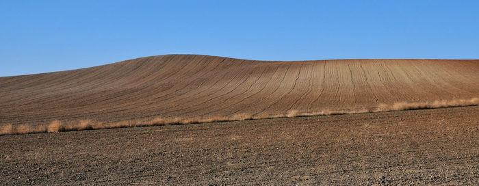 Scenic view of arid landscape against clear blue sky