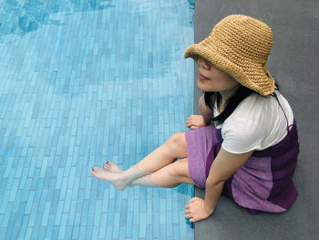 Full length of a girl sitting on swimming pool