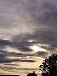 Low angle view of silhouette trees against cloudy sky