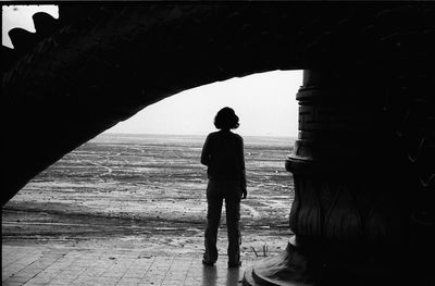 Silhouette man standing by sea against sky