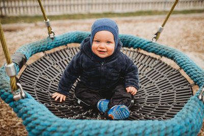 Full length of baby boy sitting in park