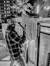 Portrait of smiling man playing musical instrument at night