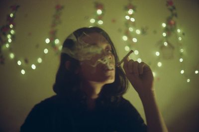 Portrait of young woman holding illuminated lighting equipment