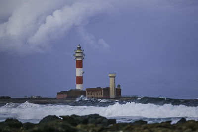 Lighthouse by sea against sky