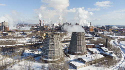 Smoke emitting from factory against sky during winter