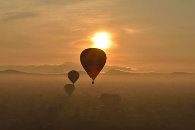 Hot air balloon flying against sky during sunset