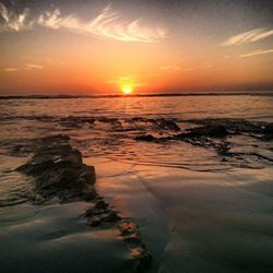 Scenic view of sea against dramatic sky during sunset