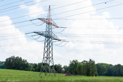 Low angle view of electricity pylon on field against sky