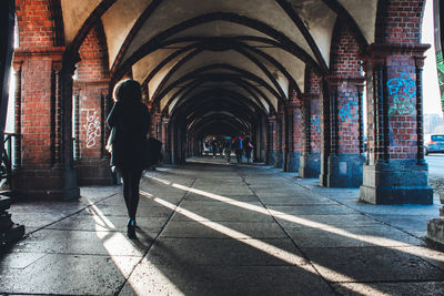 Rear view of woman walking in colonnade