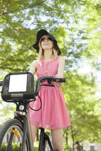 Woman in pink dress riding bicycle in park