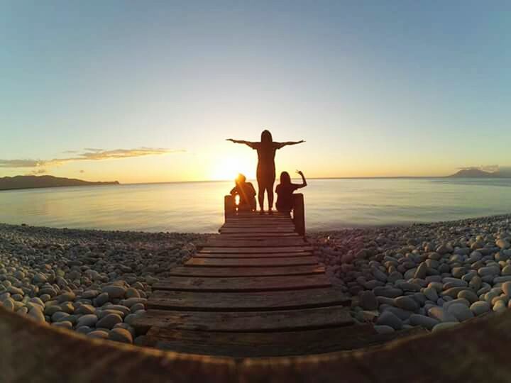 SILHOUETTE PEOPLE STANDING ON SHORE AGAINST SKY DURING SUNSET