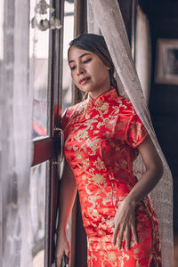 Portrait of young woman standing by window