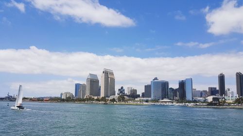 Sea by modern buildings in city against sky