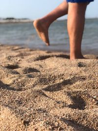 Low section of man walking on shore at beach