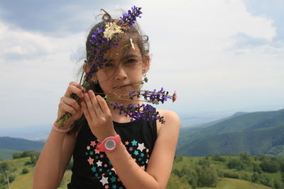 Portrait of woman with pink flowers against sky