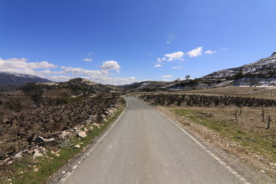 Empty road amidst mountains against sky