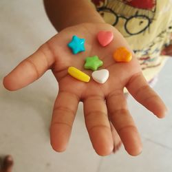 Low section of child holding multi colored candies