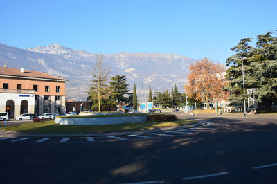 Road by trees against clear blue sky