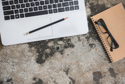 Directly above shot of book with pencil and laptop on table