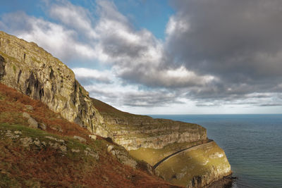 Scenic view of sea by cliff against sky