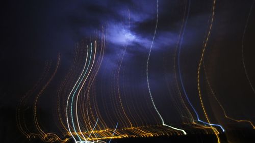 Low angle view of colorful light trails against sky at night