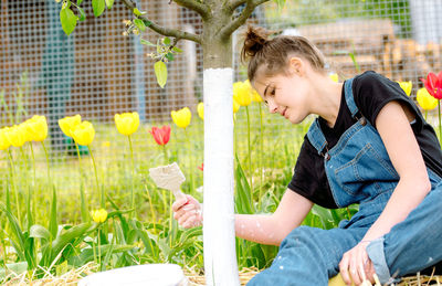 Side view of smiling woman holding plant