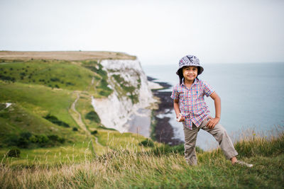 Portrait of boy standing on cliff against sky