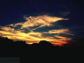 Low angle view of silhouette trees against dramatic sky