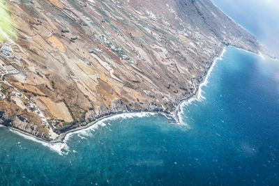 Aerial view of sea and mountains against blue sky