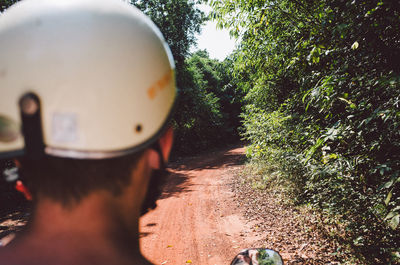 Man wearing helmet while riding motorcycle on dirt road