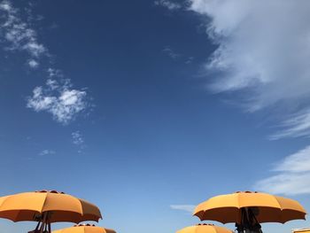 Low angle view of parasols against blue sky