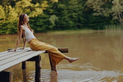 Full length of woman sitting on lake