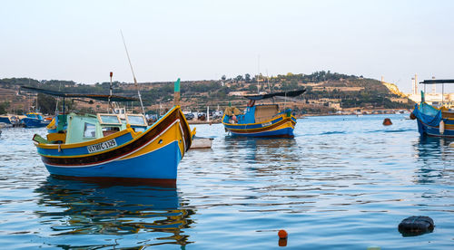 Boats moored in sea against sky in city