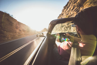 Rear view of man driving car against sky