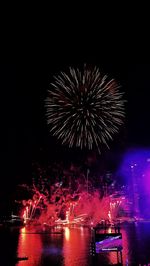 Low angle view of firework display over river at night